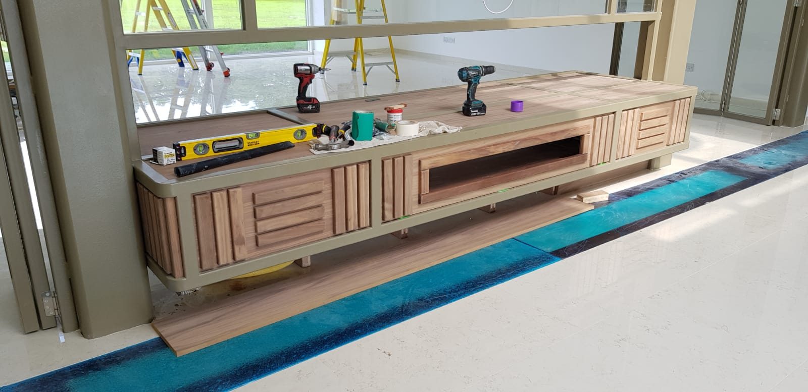 Floating media unit with slatted timber fronts under a window